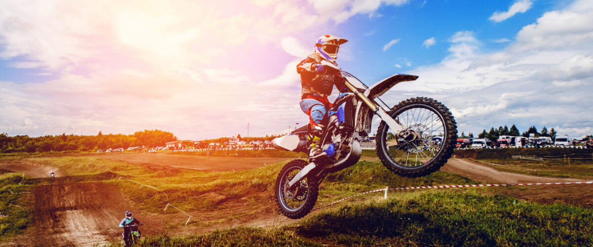 racer on mountain bike participates in motocross race, takes off and jumps on springboard, against the background of the participants. Close-up. concept of extreme rest, sports racing. ray of light