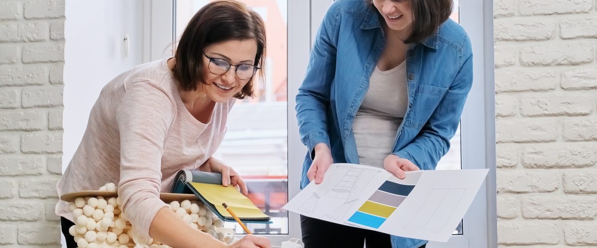 Interior design, two working colleagues designers, or decorator and client choosing curtain fabrics, women looking at samples discussing curtain models